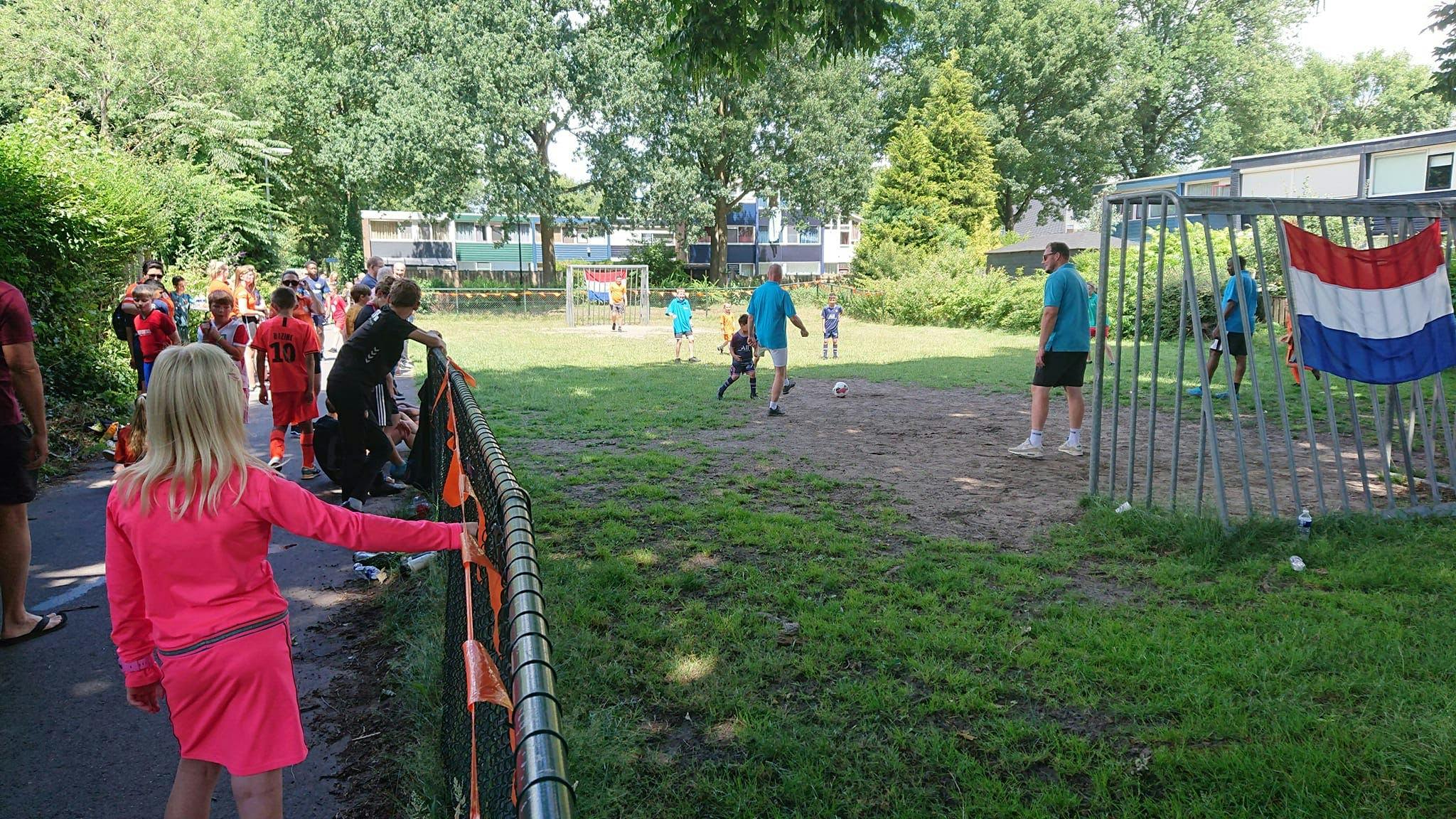 Kinderen en volwassenen voetballend op het grasveld.